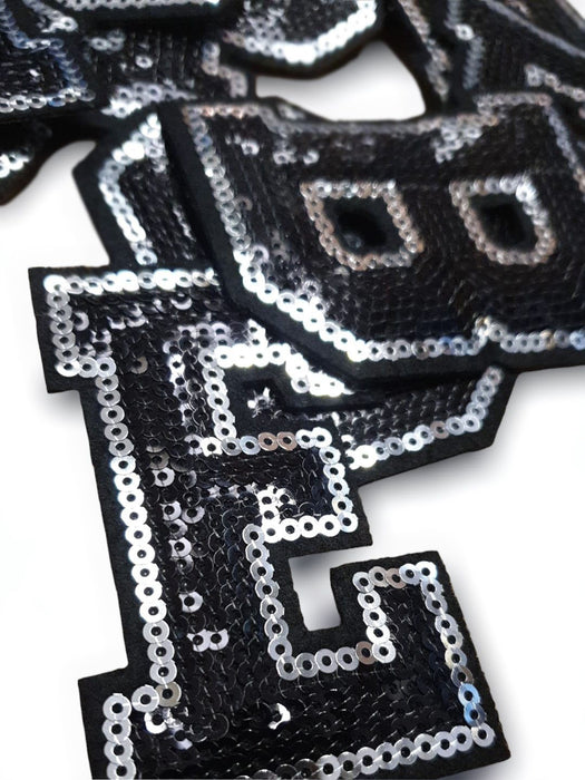 Black and silver sequin iron on patch letters close-up of letter E