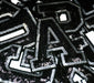 Black and silver sequin iron on patch letters, close up of letter A on other letters